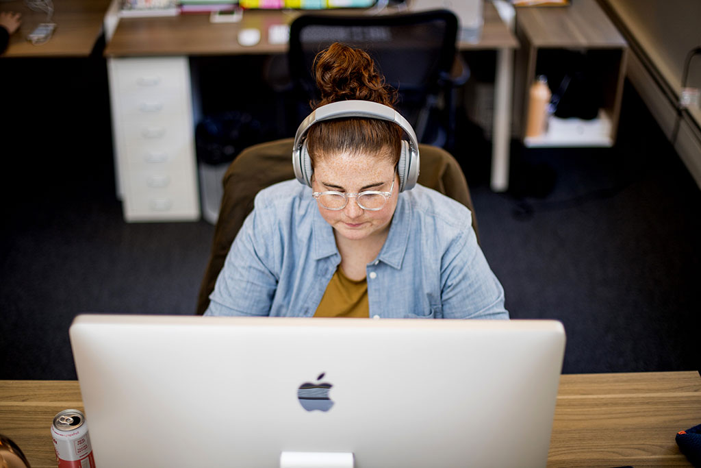 Ali works at her computer with headphones on